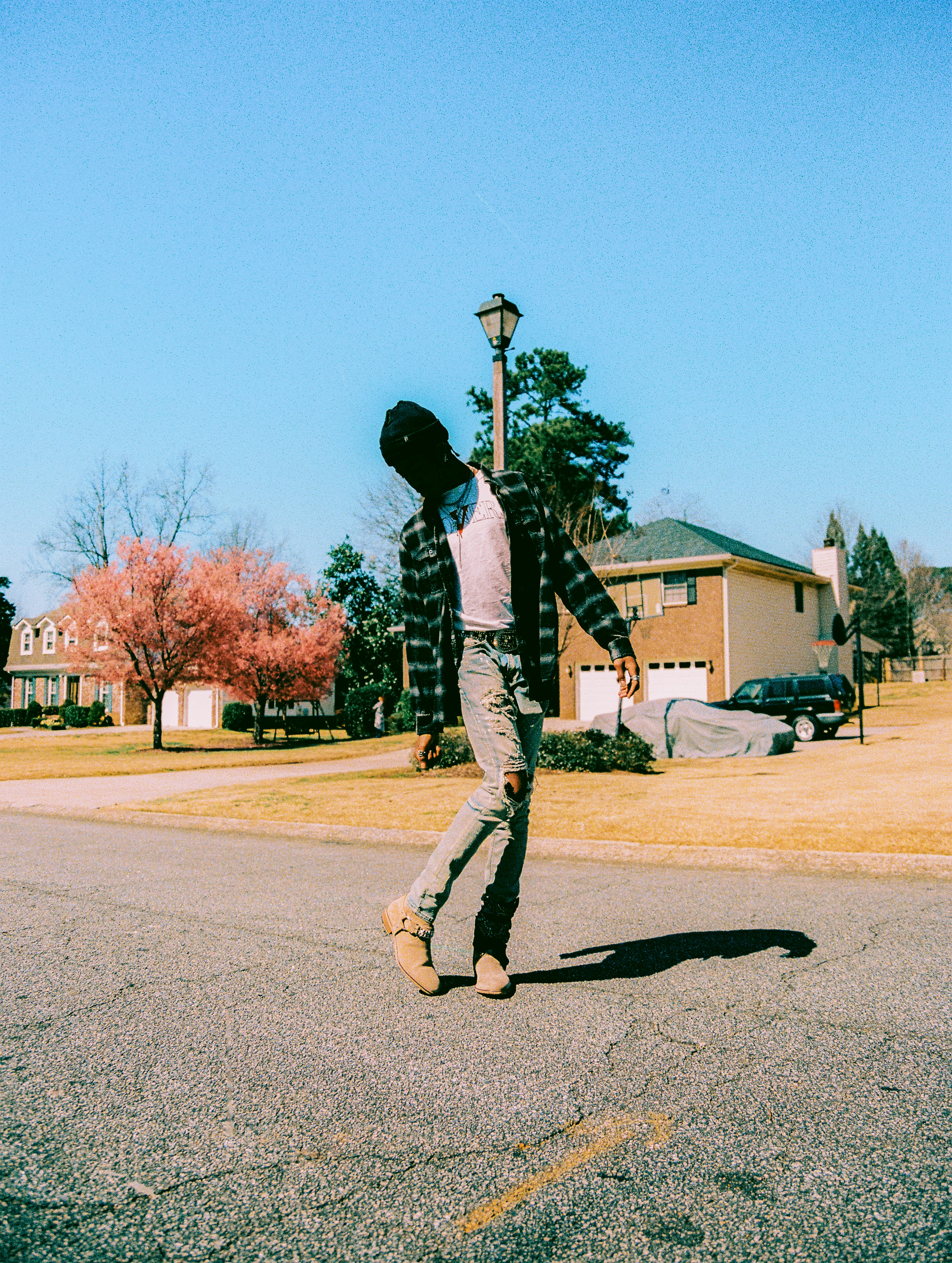 man in black jacket and gray pants walking on gray asphalt road during daytime